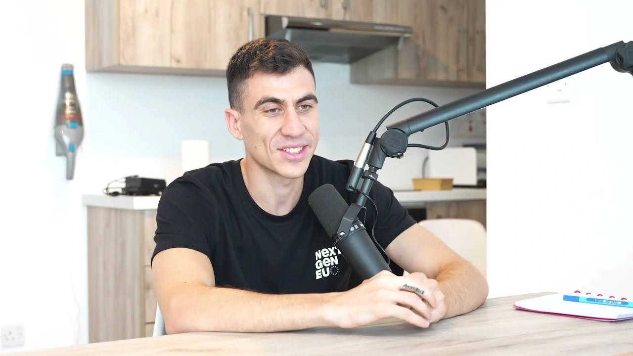 Fidias listening and responding at the microphone in his podcast studio